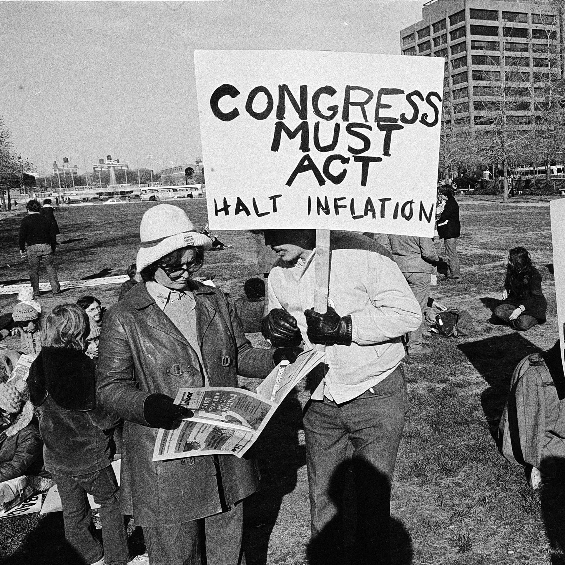 Protesters holding a sign reading “Congress must act, halt inflation”