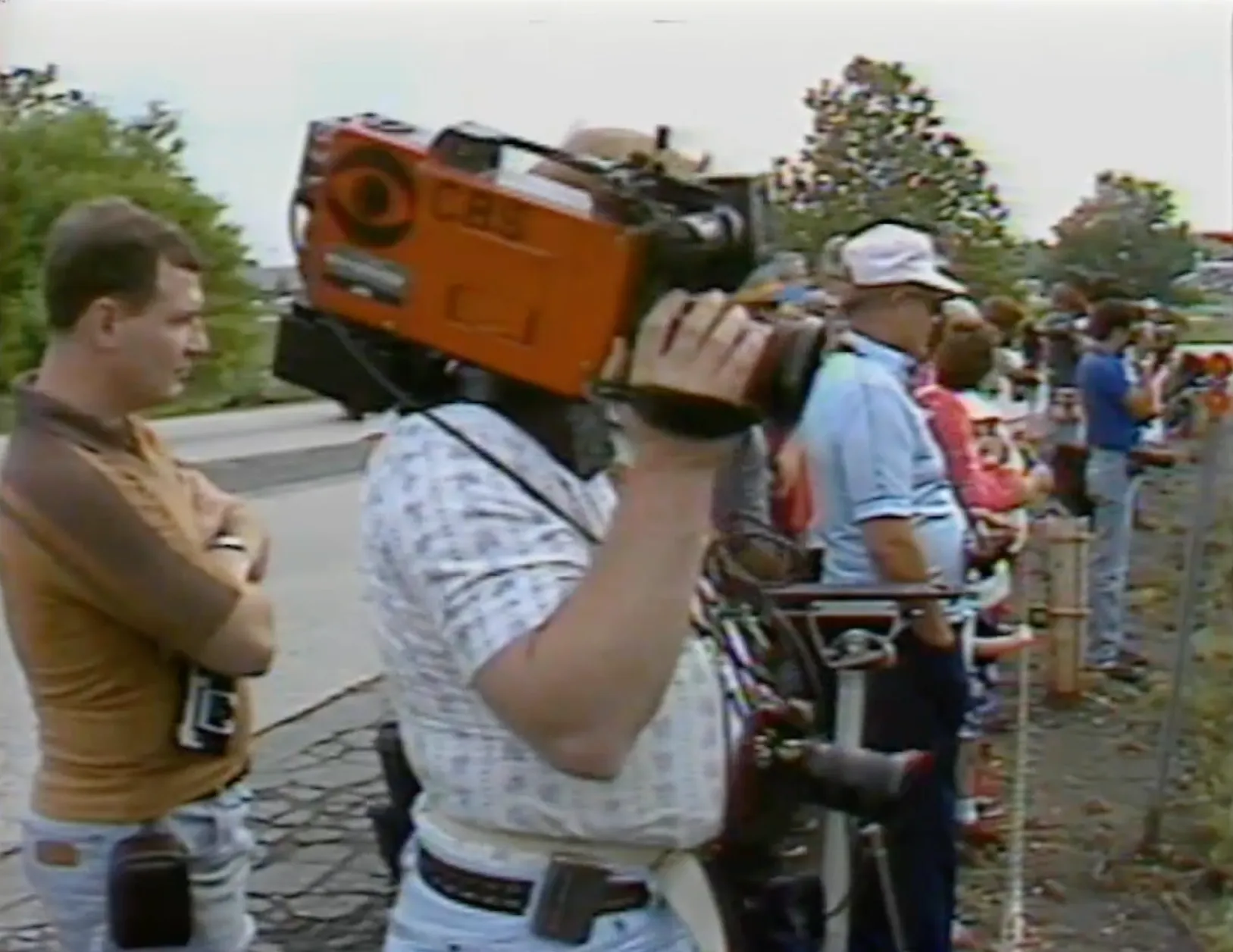 A news cameraman filming the billboard from the roadside